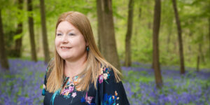 Hannah looking into distance in bluebell woods.