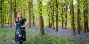 Hannah with hands on hips in bluebell woods.