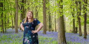 Hannah with hands on hips in bluebell woods.