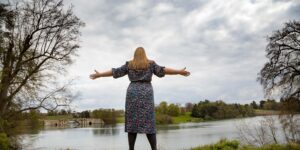 Hannah with arms spread out looking over a lake.