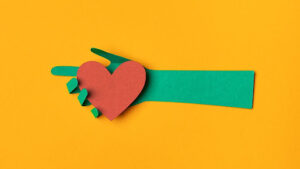 Illustration of a green arm and hand holding a heart.